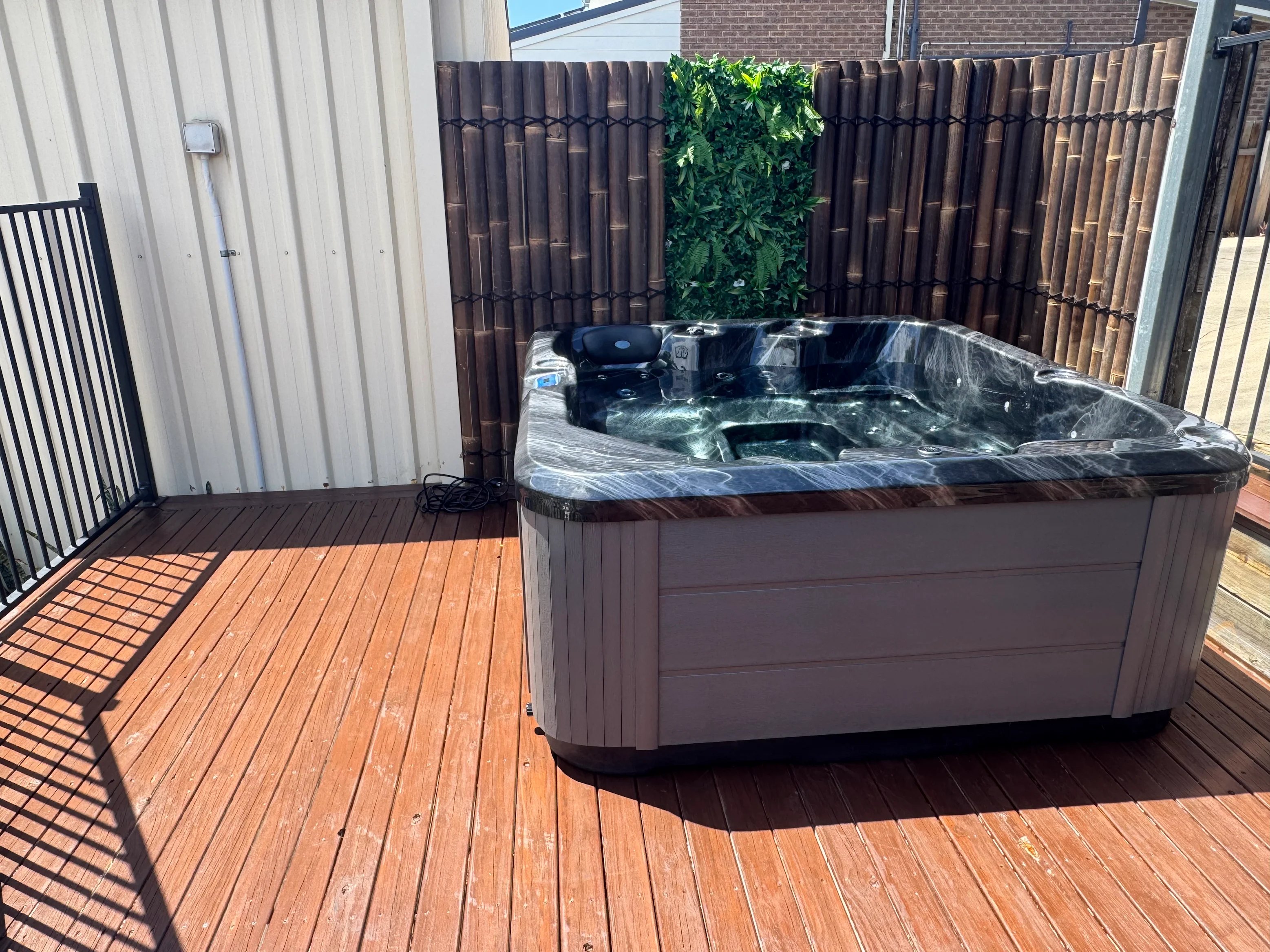 Spa on a timber deck against a fence with screening plants