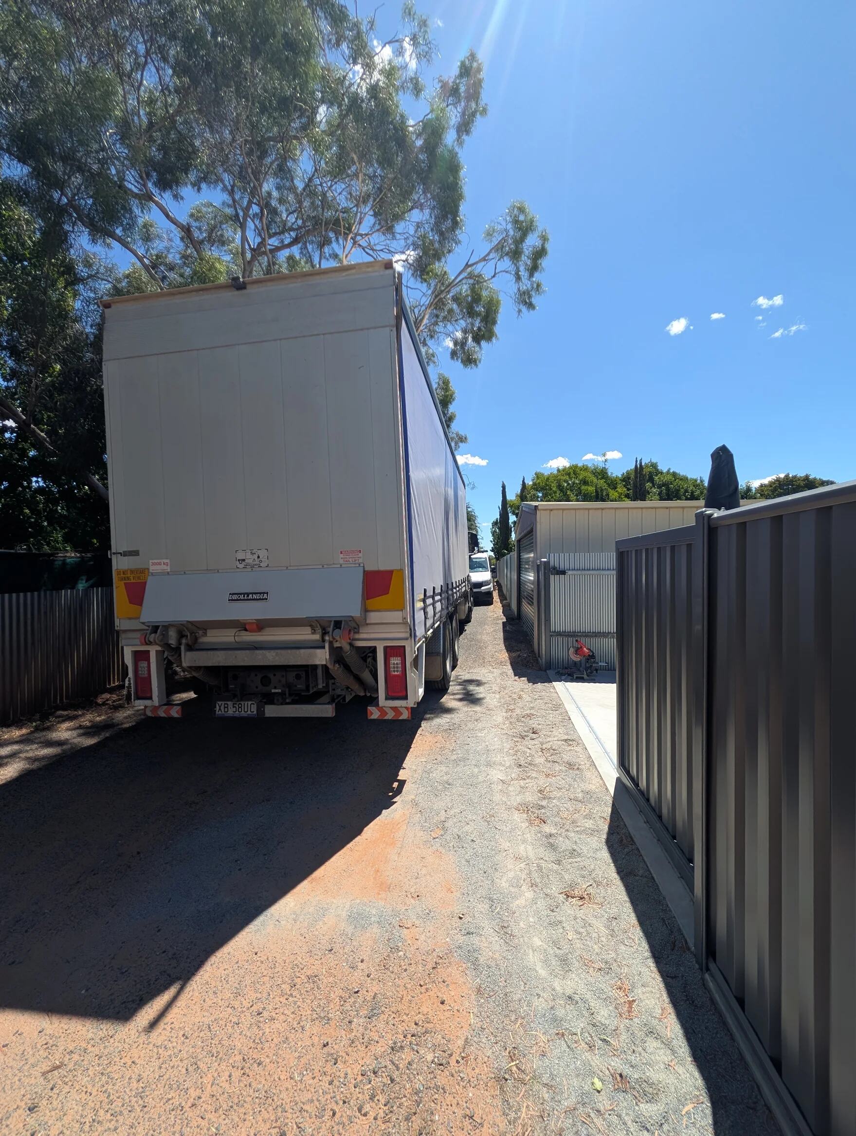 A delivery truck reversed down a narrow side access beside a customer's home