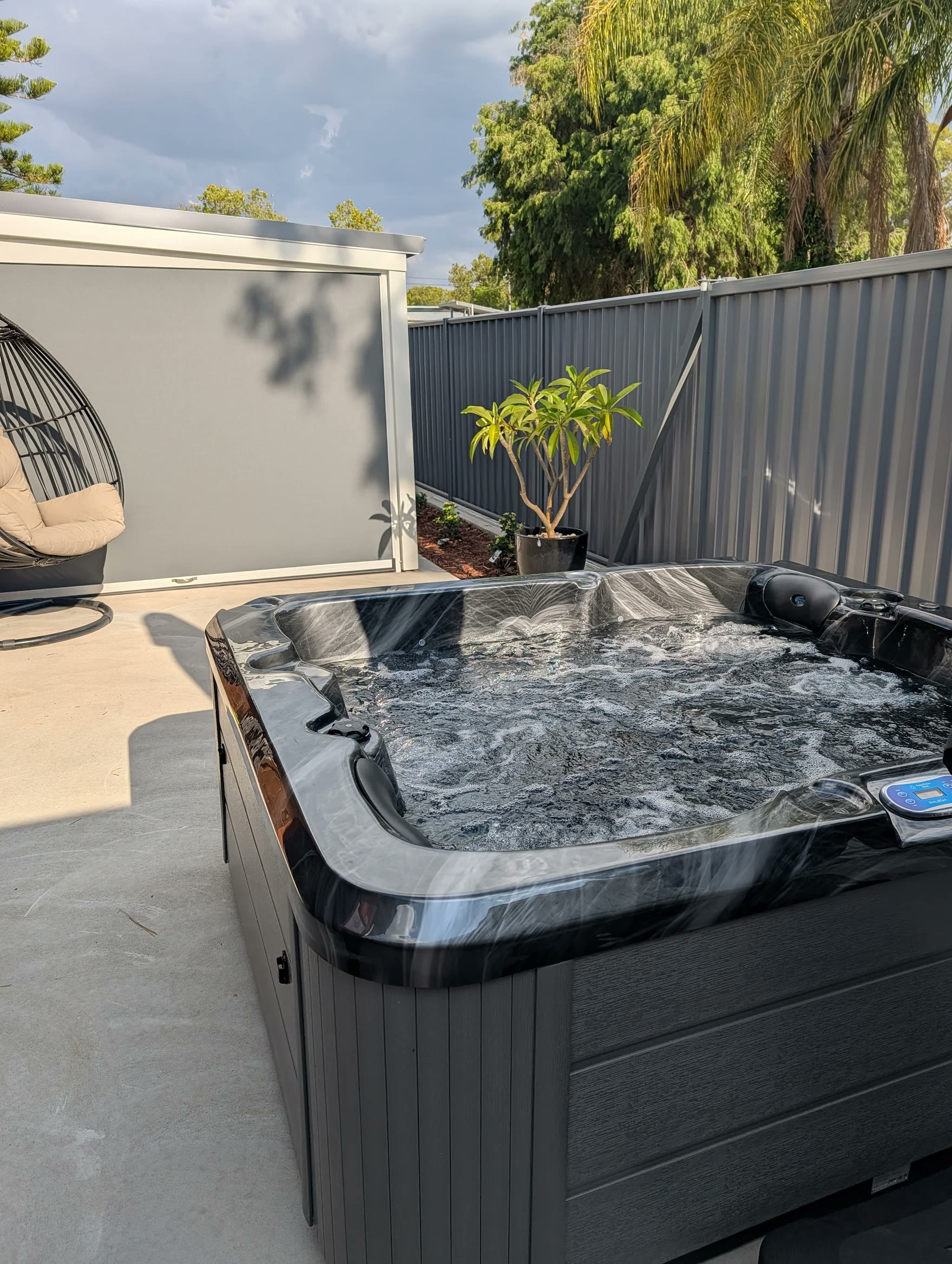 Black-marble spa running on a rendered patio, supplied by an Aqua Pulse customer