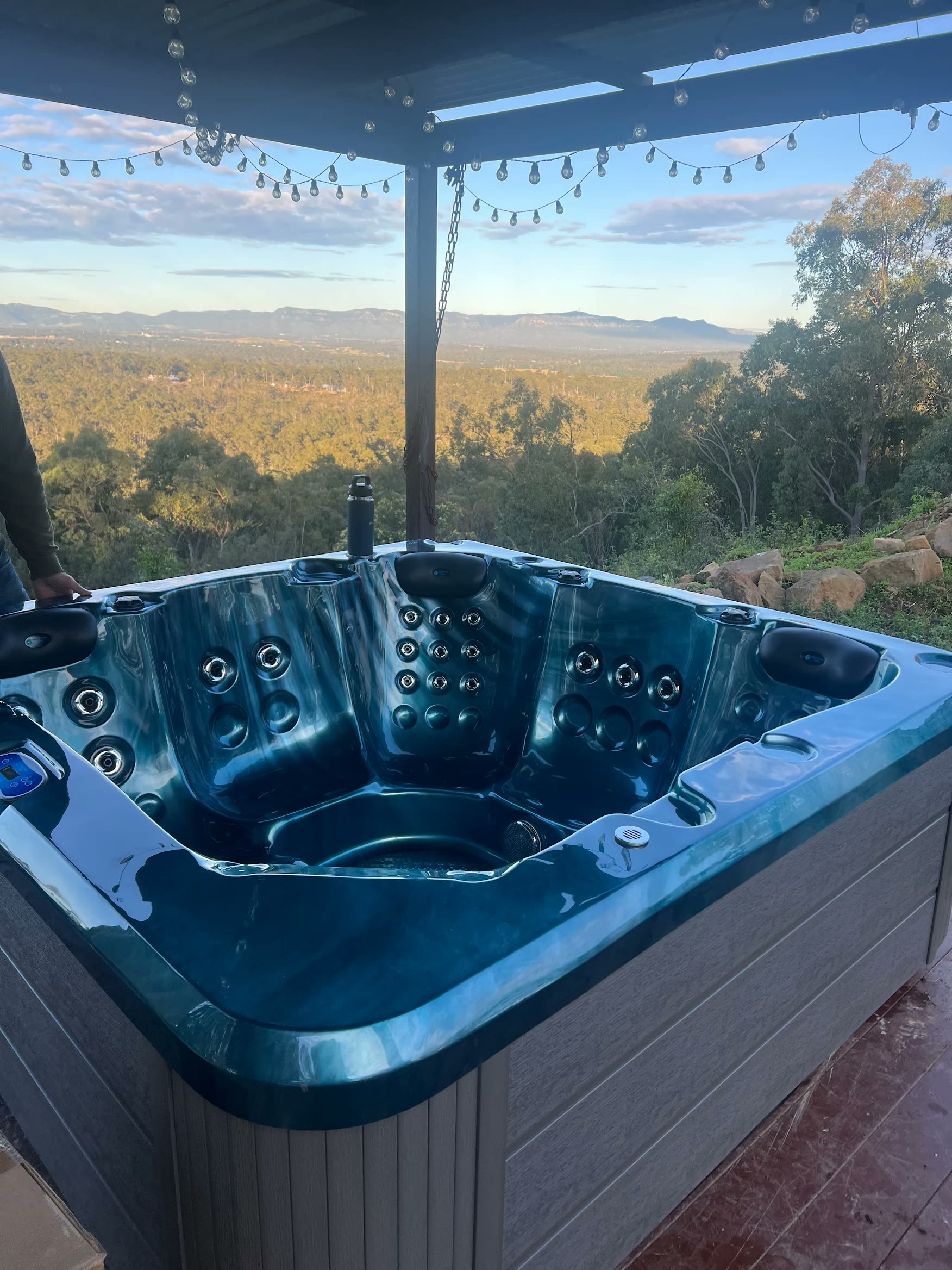 Teal spa in golden-hour light overlooking a valley, supplied by an Aqua Pulse customer
